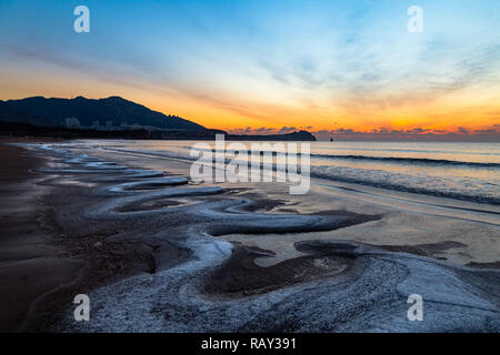 24 Jan 2018, Qingdao, Shandong. Sunrise Shilaoren sulla spiaggia, in una mattina così freddo che l acqua del mare viene trasformata in ghiaccio Foto Stock