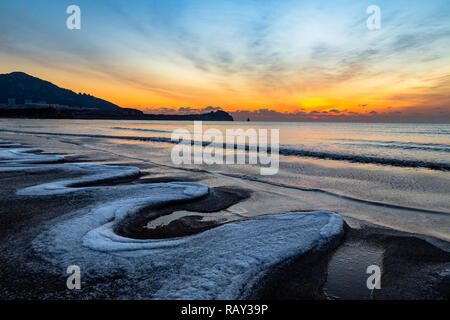 24 Jan 2018, Qingdao, Shandong. Sunrise Shilaoren sulla spiaggia, in una mattina così freddo che l acqua del mare viene trasformata in ghiaccio Foto Stock