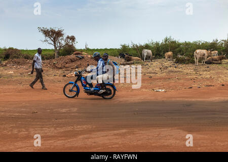 Bissau, Repubblica di Guinea Bissau - Febbraio 6, 2018: due uomini su una motocicletta su una strada sterrata alla periferia della città di Bissau in Guinea Bissau, Foto Stock