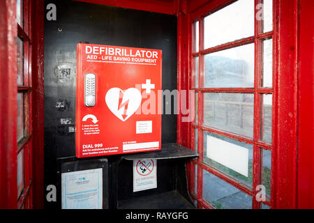 La defibrillazione di emergenza il defibrillatore semiautomatico esterno (AED) situato in un vecchio telefono rosso scatola in un villaggio di Lancashire Foto Stock