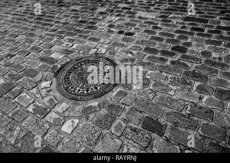 Una strada di ciottoli di Berlino in Germania con la torre della televisione su un chiusino (bianco e nero) Foto Stock