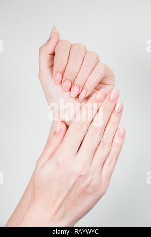 Primo piano della femmina di due mani bianche con il vecchio gel manicure lucidato necessitano di correzione dopo diverse settimane di usura. Verticale fotografia a colori. Foto Stock