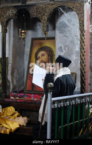 Ortodossa Etiope di Monaco in preghiera dentro la Chiesa Copta Cappella di San Michele Arcangelo nella sezione inferiore di Deir El-Sultan monastero etiope che si trova sul tetto della chiesa del Santo Sepolcro nella città vecchia di Gerusalemme Est Israele Foto Stock