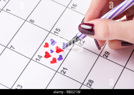 Ragazza del disegno a mano i cuori in calendario con un pennarello per il giorno di San Valentino. Amore e San Valentino vacanza concetto. Close up, il fuoco selettivo Foto Stock