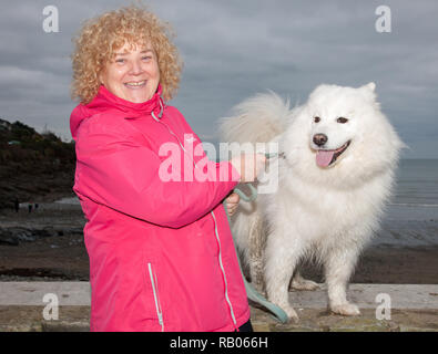 Fountainstown, Cork, Irlanda. 05 gennaio. 2019. Jane Morley dal National Learning Network, Hollyhill, con il suo cane Samoiedo Harry sostenendo i nuotatori che hanno preso parte al Carrigaline cantare o nuotare evento per raccogliere fondi per l'irlandese del motoneurone associazione malattia a Fountainstown Beach, Co. Cork, Irlanda. Credito: David Creedon/Alamy Live News Foto Stock