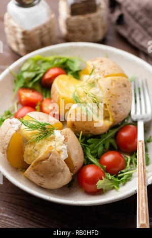 Patate al forno ripiene con formaggio e salsa con rucola fresca insalata di pomodoro Foto Stock