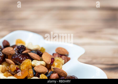 Frutta secca in piastra bianca sul tavolo di legno. Mix di diverse varietà di frutta e bacche, vitamine. Copia con spazio per il testo Foto Stock