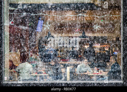 A Belgrado, in Serbia - Dicembre 15, 2018:persone di mangiare in un ristorante fast food in un giorno di neve, dall'esterno attraverso il vetro del finestrino Foto Stock