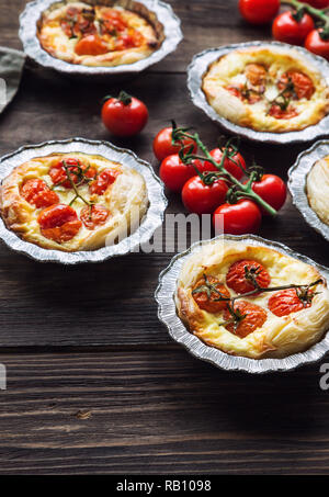 Fresche crostate con pomodorini e formaggio di capra su legno rustico sfondo. Foto Stock