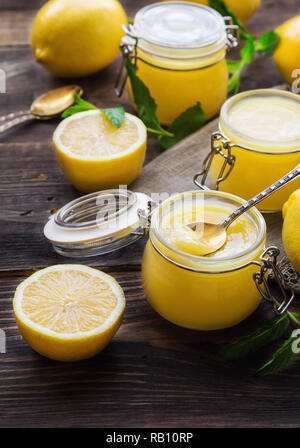 Freschi Fatti in casa cagliata di limone in vasetti di vetro su legno rustico sfondo. Messa a fuoco selettiva. Foto Stock