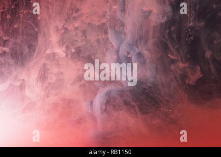 Una goccia di vernice si dissolve in acqua. La vernice rossa è miscelata con acqua. Un pattern astratti. Foto Stock