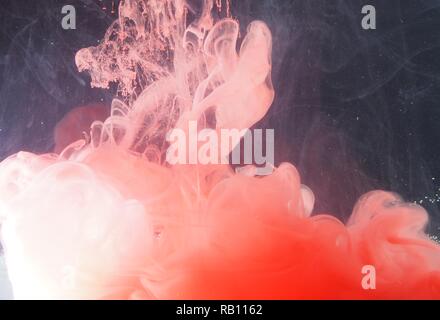 Una goccia di vernice si dissolve in acqua. La vernice rossa è miscelata con acqua. Un pattern astratti. Foto Stock