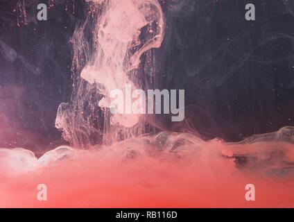 Una goccia di vernice si dissolve in acqua. La vernice rossa è miscelata con acqua. Un pattern astratti. Foto Stock