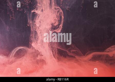 Una goccia di vernice si dissolve in acqua. La vernice rossa è miscelata con acqua. Un pattern astratti. Foto Stock