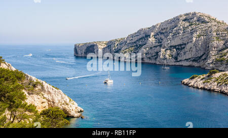 Vista panoramica della PAC Morgiou sulla costa mediterranea nei pressi di Marsiglia, Francia, con crociera di barche a motore e barche a vela ormeggio in acqua blu. Foto Stock