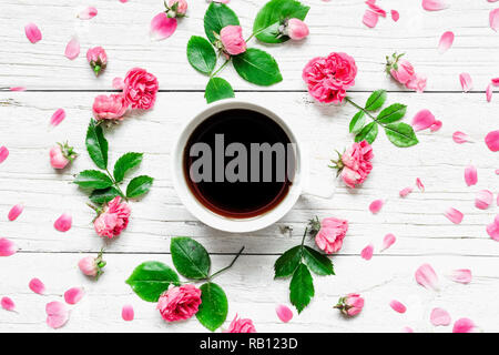 Composizione di fiori. tazza di caffè o di tè nero in cornice fatta di freschi fiori rosa bianca su sfondo di legno. Piatto. laici mock up. vista superiore Foto Stock