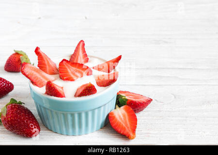 Un sano di yogurt alla fragola con frutti di bosco freschi su bianco tavolo in legno. Colazione sana. close up con spazio di copia Foto Stock