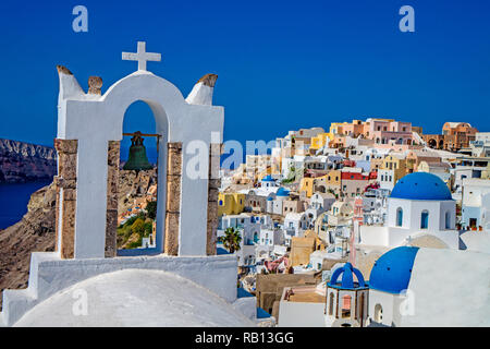 Colorata città di Oia a Santorini in Grecia con una croce di campana e cupole Foto Stock