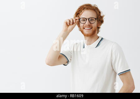 Vita-up shot di amichevole attraente redhead giovane studente maschio con la barba toccando i bicchieri e sorridente ampiamente con la fotocamera mentre si parla in modo informale e avente interessante idea circa il recente dibattito Foto Stock