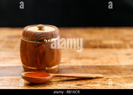 Chiuso il barile con il miele e il cucchiaio di legno su una tavola di legno. Canna. Lo spazio al di sotto del testo. Copia dello spazio. Close-up. Foto Stock