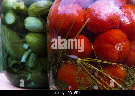 In casa conserve di pomodori e cetrioli in un vasetto di vetro Foto Stock