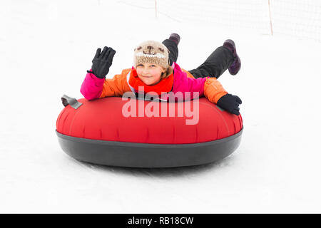 Bambino ragazza su tubi di neve in discesa al giorno d'inverno. Foto Stock