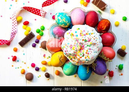 Composizione di festa in stile rustico, Pasqua pasto prima colazione. Torta di Pasqua e uova dipinte di bianco su un tavolo di legno. Vista superiore piatta sullo sfondo dei laici. Foto Stock