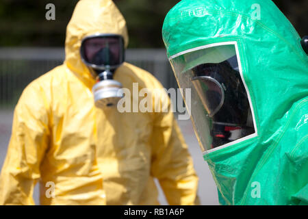 Due uomini in abbigliamento protettivo pulizia dopo l incidente chimico o la radiazione incidente. L'ingranaggio gonfiabile a destra protegge contro la contaminazione Foto Stock