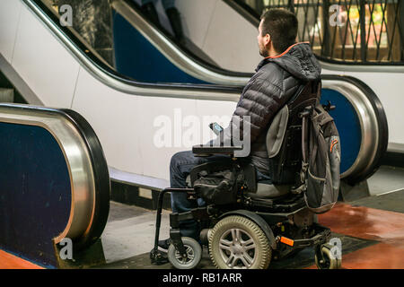 Vista posteriore di un uomo disabili su sedia a rotelle nella parte anteriore delle scale mobili Foto Stock