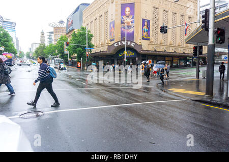 AUCKLAND NUOVA ZELANDA - 23 dicembre 2018; persone attraversate Queen Street e Wellesley Street intersezione di fronte storico Teatro Civico sul giorno di pioggia Foto Stock