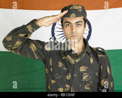 Ritratto di soldato indiano vestito in uniforme salutando con l Indian bandiera nazionale IN BACKGROUND Foto Stock