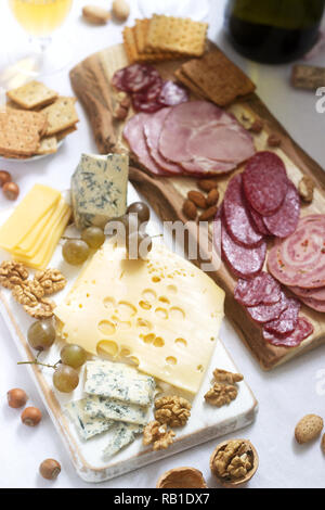 Antipasto di vari tipi di salumi, carni, formaggi e crackers su una tavola di legno, servita al vino. Foto Stock