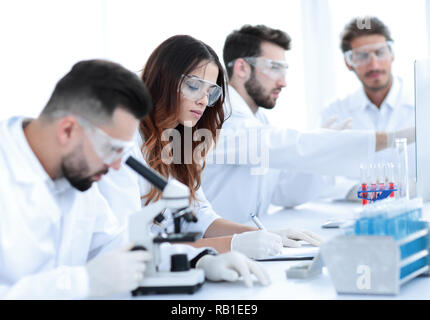 Scienziato cercando in una seduta di microscopio in laboratorio. Foto Stock