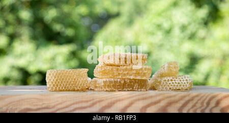 Fresca luce Ape Miele in pezzi di favi su una tavola di legno tavolo rustico con sfocatura dello sfondo. Foto Stock