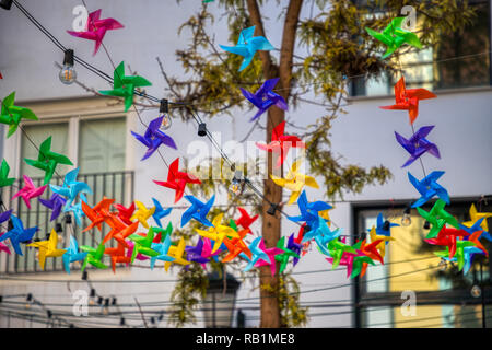 Luminoso multicolore decorazioni girandola infilate attraverso un cortile per una celebrazione diurna Foto Stock