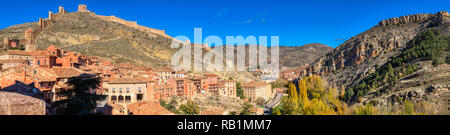 Una panoramica di una foto scattata da dentro la città di Albarracin in Spagna in cui l'antico muro può essere visto lungo con i tetti e le montagne Foto Stock
