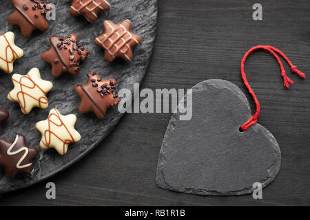 A forma di stella cioccolatini on dark testurizzato con sfondo nero ardesia cuore di pietra Foto Stock
