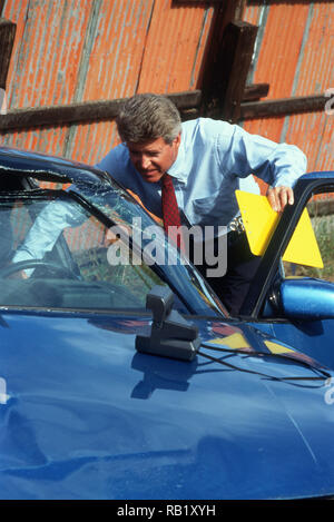 Il responsabile della gestione delle richieste di rimborso dell'assicurazione ispeziona una recente auto distrutta in un cantiere navale, USA 1993 Foto Stock