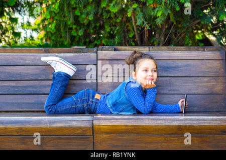 Un bambino gioca un tablet e sorrisi in un cafè all'aperto. Infanzia Foto Stock