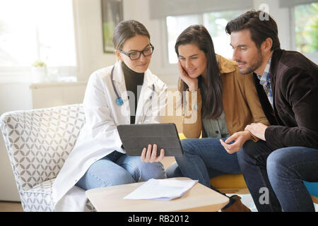 Felice medico con paio di pazienti in un ufficio moderno Foto Stock