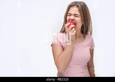 Immagine della giovane donna di mordere il pezzo da apple. Ella si ritira. Iolated su sfondo bianco. Foto Stock