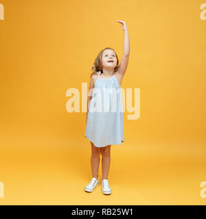 Un bambino piccolo che misura la sua altezza su uno sfondo giallo. Concetto di sviluppo, obiettivo, il successo Foto Stock