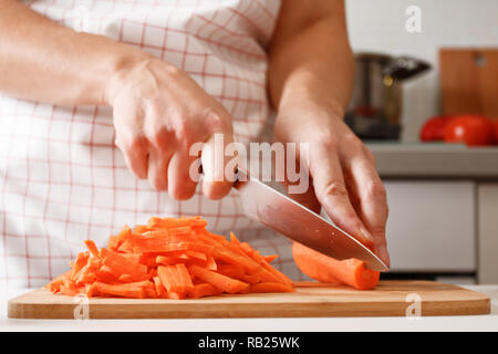 Donna che taglia la carota fresca su un asse di legno in cucina Foto stock  - Alamy