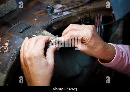 Gioielliere lavorando con un ago file un anello d'oro su un vecchio banco in autentici gioielli workshop Foto Stock