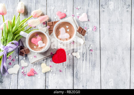 Il giorno di San Valentino trattare le idee, due tazze di cioccolata calda a bere con marshmallow Cuori rosa rosso di colore bianco con pezzetti di cioccolato, granelli di zucchero, il legno vecchio Foto Stock