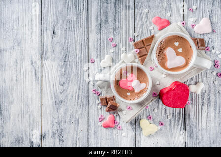 Il giorno di San Valentino trattare le idee, due tazze di cioccolata calda a bere con marshmallow Cuori rosa rosso di colore bianco con pezzetti di cioccolato, granelli di zucchero, il legno vecchio Foto Stock