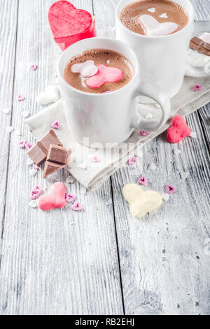 Il giorno di San Valentino trattare le idee, due tazze di cioccolata calda a bere con marshmallow Cuori rosa rosso di colore bianco con pezzetti di cioccolato, granelli di zucchero, il legno vecchio Foto Stock