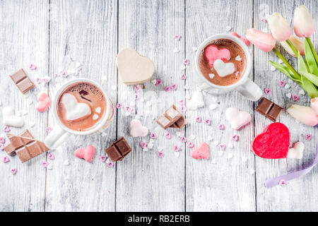 Il giorno di San Valentino trattare le idee, due tazze di cioccolata calda a bere con marshmallow Cuori rosa rosso di colore bianco con pezzetti di cioccolato, granelli di zucchero, il legno vecchio Foto Stock