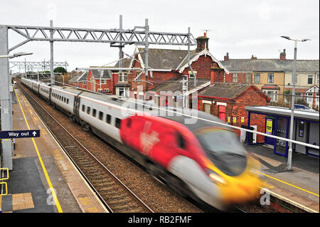 Inter City vergine treno passa attraverso una piccola stazione urbana sulla nuova elettrificata di Blackpool Preston linea sul suo modo di London Euston Foto Stock