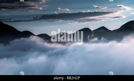 Silhouette di una catena di montagne vista da Itaipava, città di Petropolis, Stato di Rio de Janeiro, Brasile, con bassa, fitta nebbia che guarda come Foto Stock